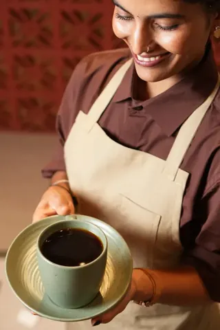 A Kora.Blr team member serving freshly brewed black coffee