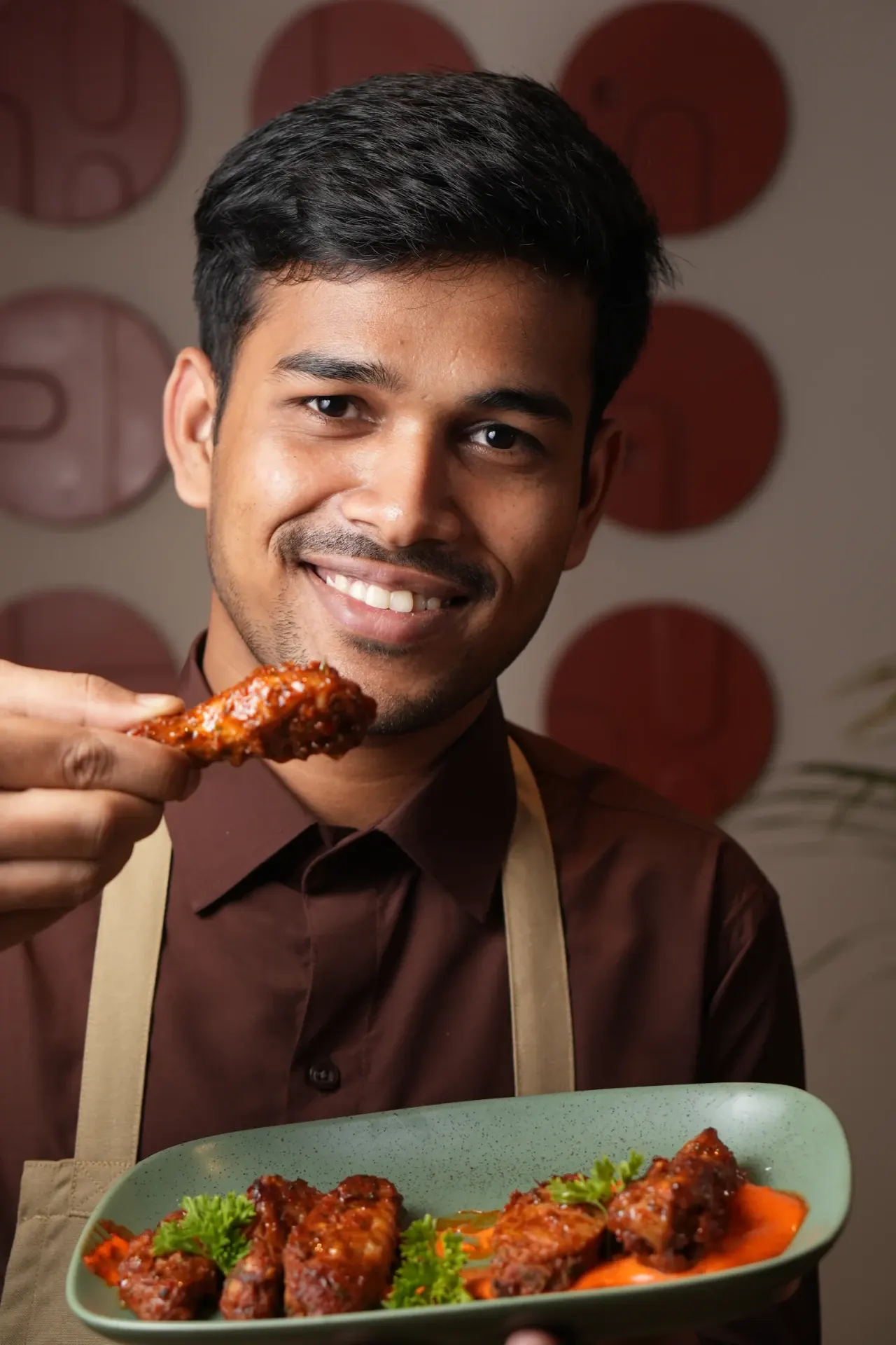 A smiling Kora.Blr team member presenting a platter of glazed bites