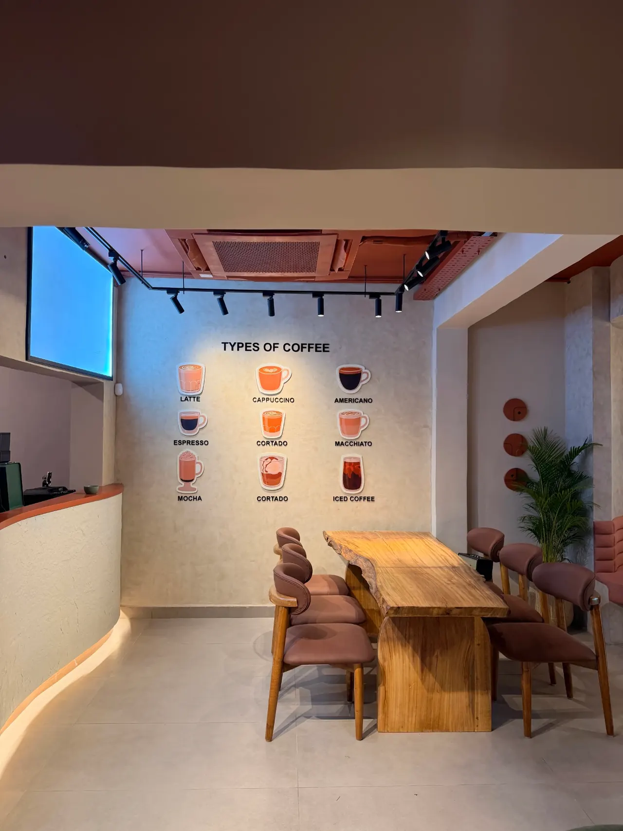 Kora.Blr café interior with a communal table and coffee wall